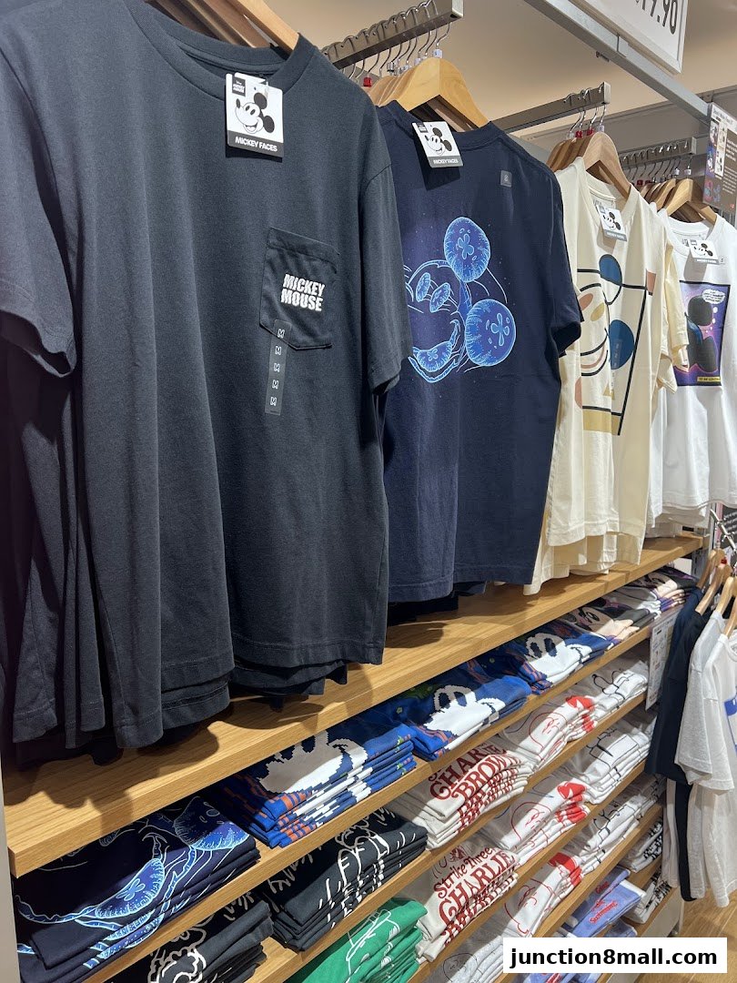 A display of graphic t-shirts, featuring Mickey Mouse and other designs, neatly folded and hung.