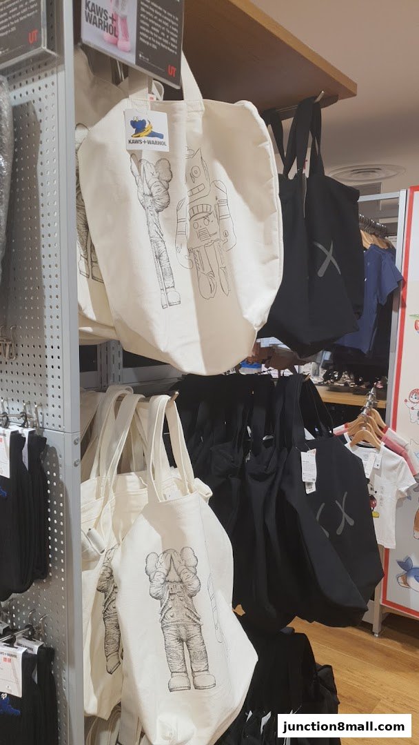 UNIQLO tote bags featuring KAWS + WARHOL designs are displayed on shelves.