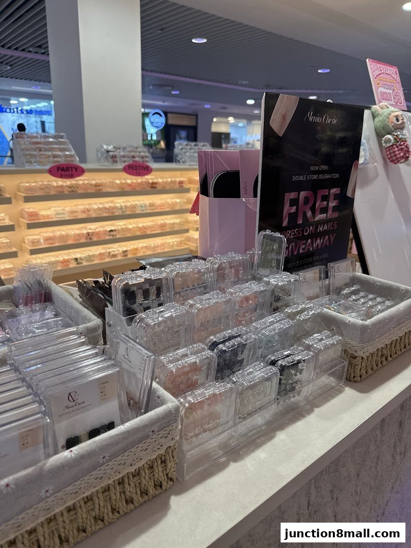 A display of various press-on nail sets and a promotional sign for a free giveaway.