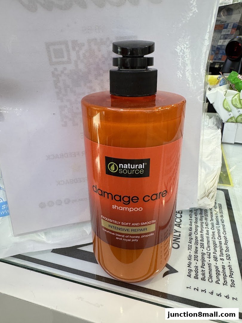 A bottle of Natural Source Damage Care Intensive Repair Shampoo with a QR code and store addresses in the background.