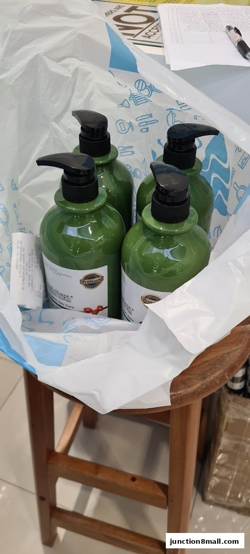 Several green pump bottles of hair care products are placed inside a white shopping bag.