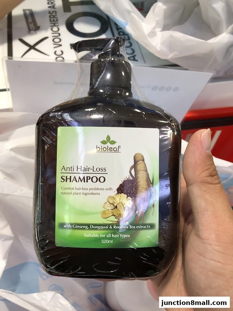 A hand holds a bottle of Bioleaf Anti Hair-Loss Shampoo with ginseng and other natural ingredients.