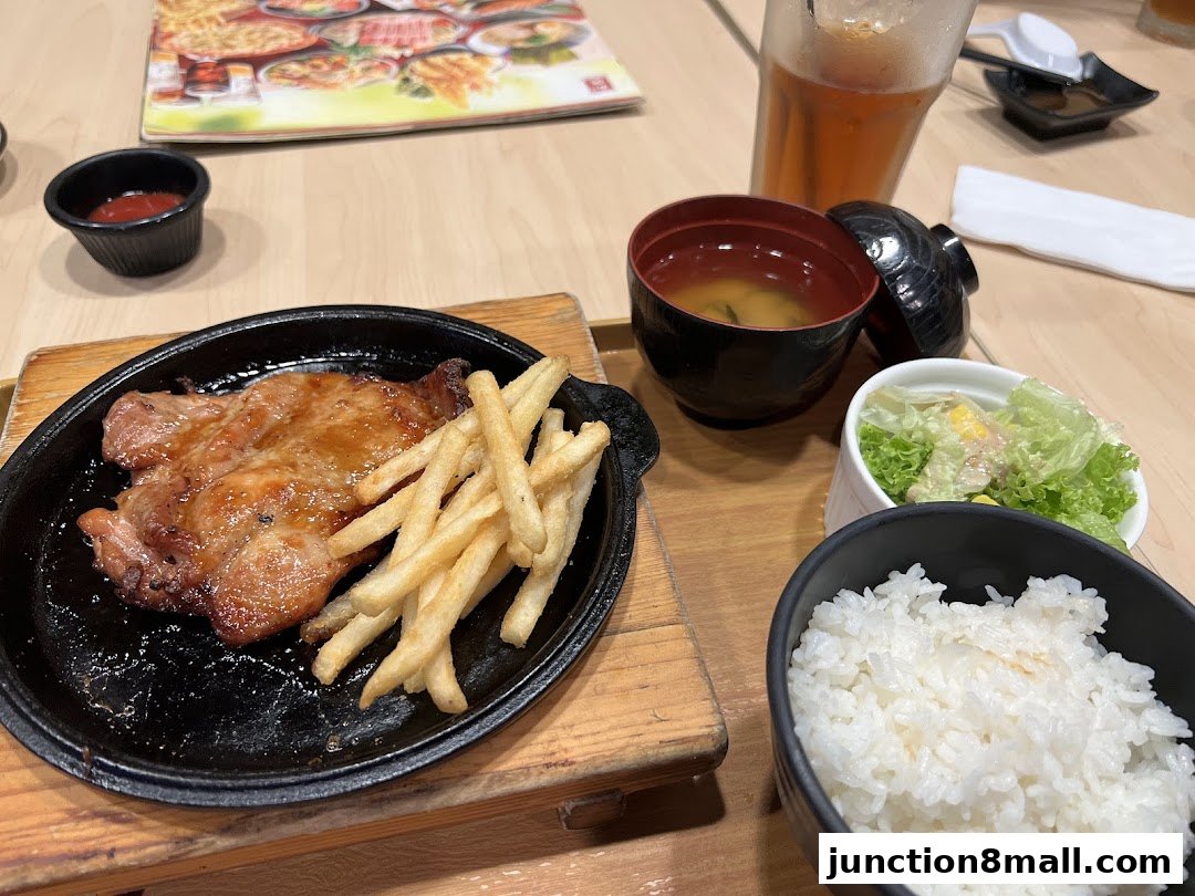 A delicious Japanese meal featuring grilled chicken, fries, rice, miso soup, and salad.