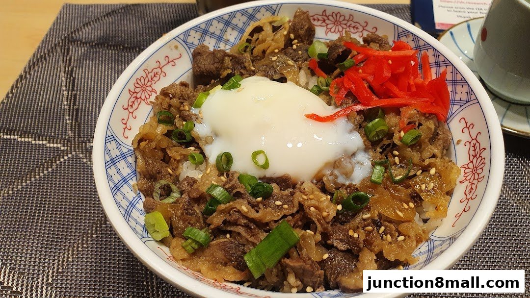 A close-up of a Japanese beef bowl with a soft-boiled egg and pickled ginger.