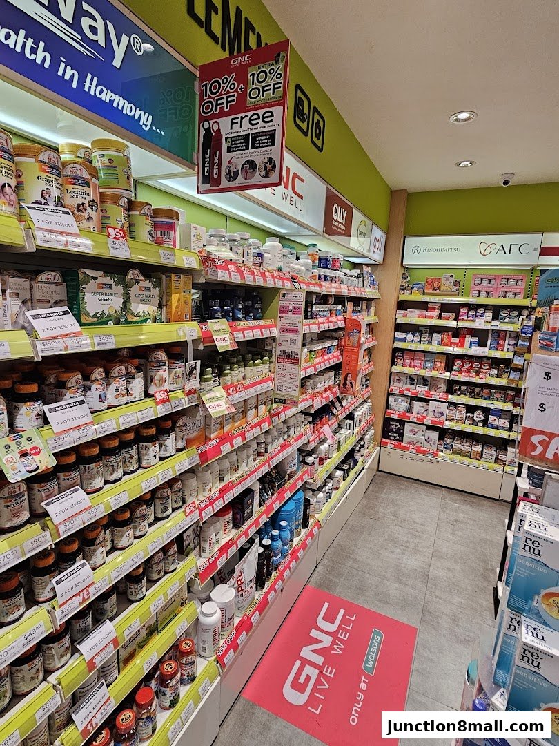 A wide aisle inside a Watsons and GNC store, showcasing shelves stocked with health supplements and vitamins.