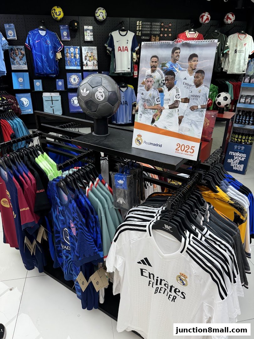 A retail store display featuring various football jerseys, a Real Madrid calendar, and football merchandise.