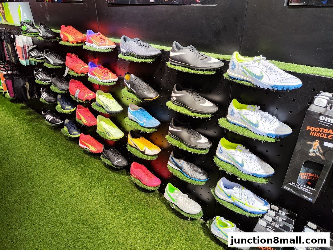 A display of various soccer cleats and athletic shoes on shelves with artificial grass.