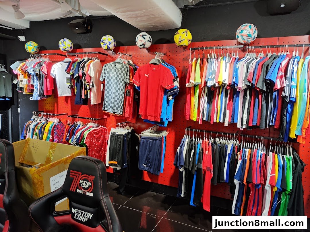 A retail store interior displaying a wide selection of sports apparel, primarily soccer jerseys and shorts.