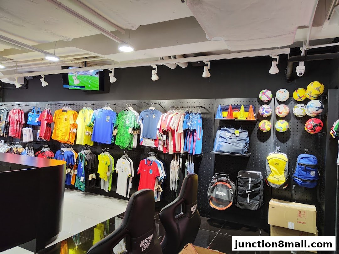 Interior of a sports apparel store showcasing jerseys, soccer balls, and bags.
