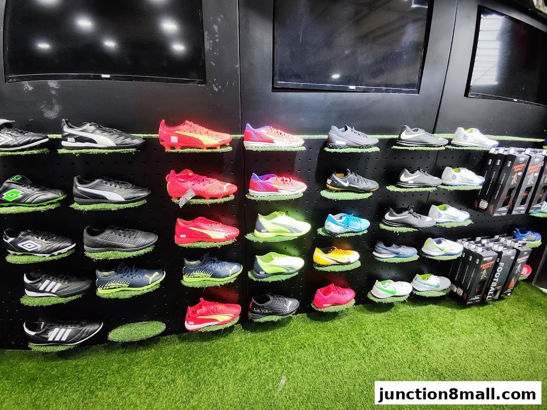A display of various soccer cleats and athletic shoes on shelves with artificial grass.