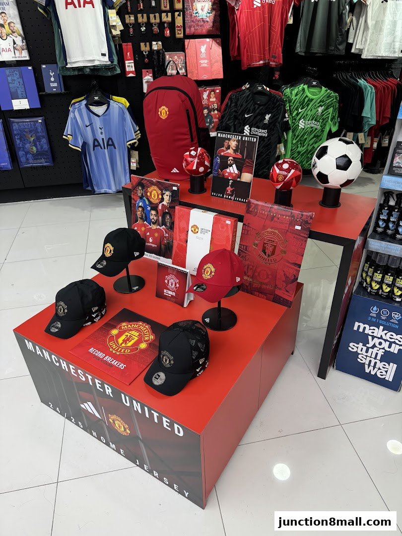 A retail display featuring Manchester United merchandise, including jerseys, caps, and footballs.
