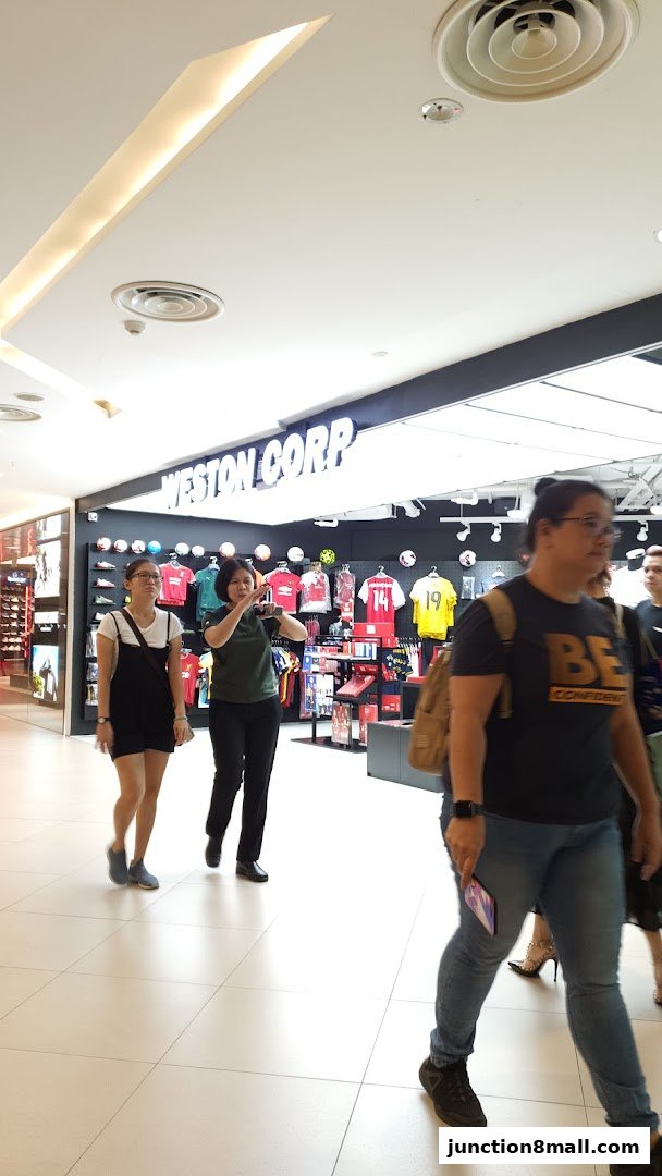 People walk past the Weston Corp store, which displays sports apparel and merchandise.