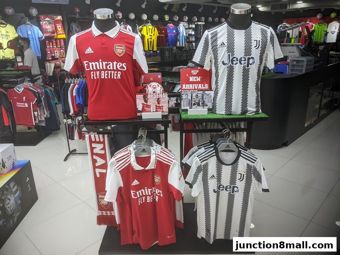 Shop interior displaying football jerseys and merchandise from Arsenal and Juventus.