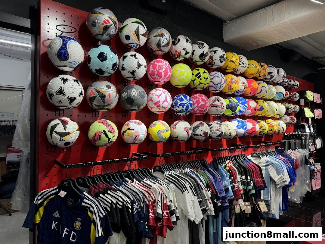 A wall display of soccer balls and sports jerseys in a retail store.