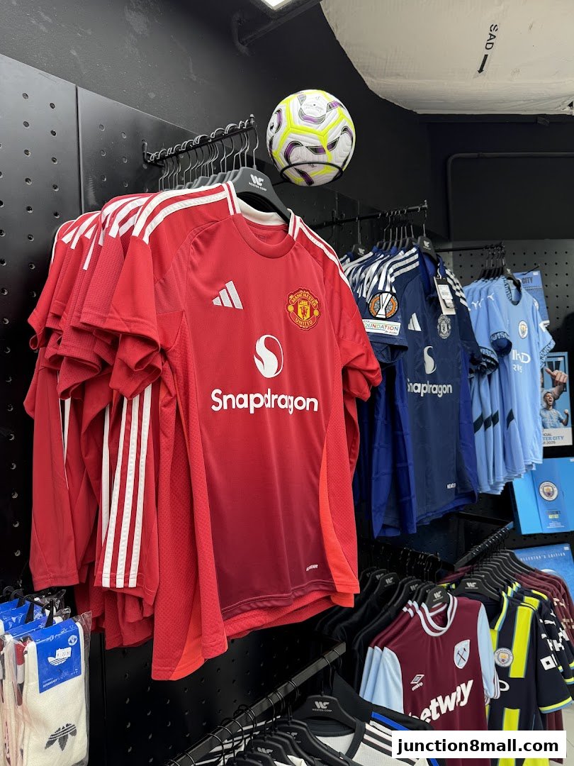 A display of football jerseys, including Manchester United, in a retail store setting.