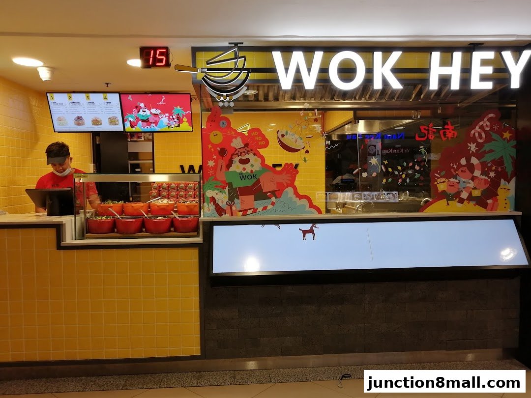 A Wok Hey shop with a staff member at the counter and festive decorations.