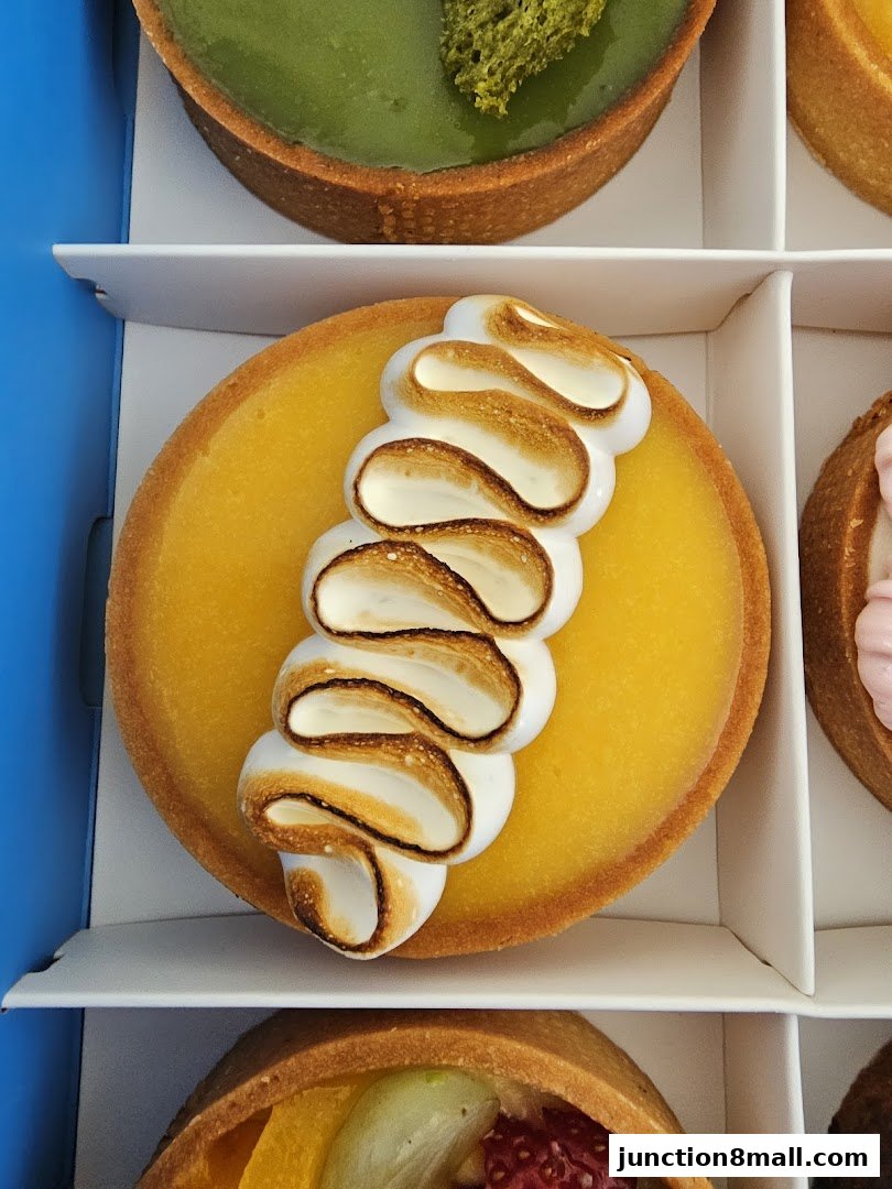 A close-up of delicious tarts, featuring a lemon meringue tart and a matcha tart.