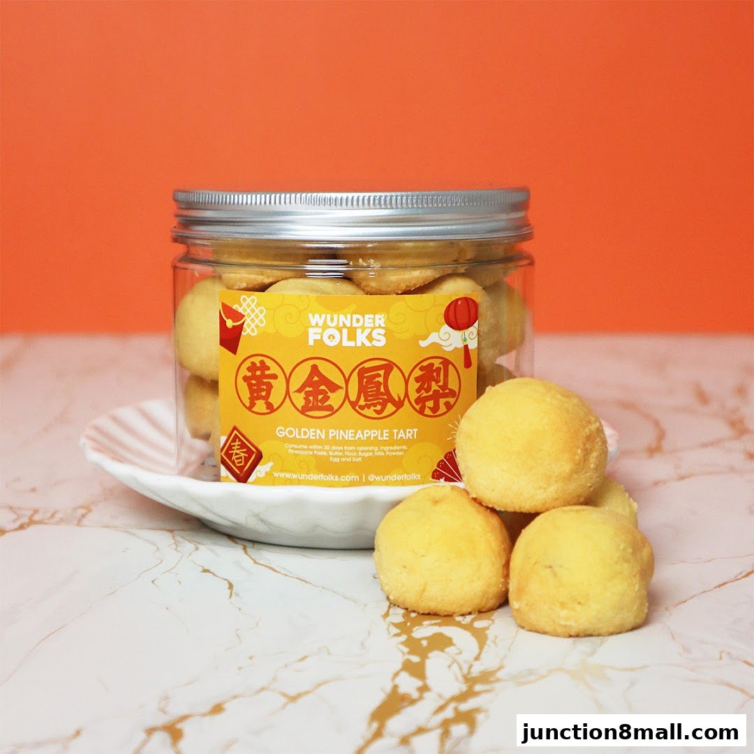 A jar of Golden Pineapple Tarts from Wunderfolks, displayed with a few tarts on a marble surface.