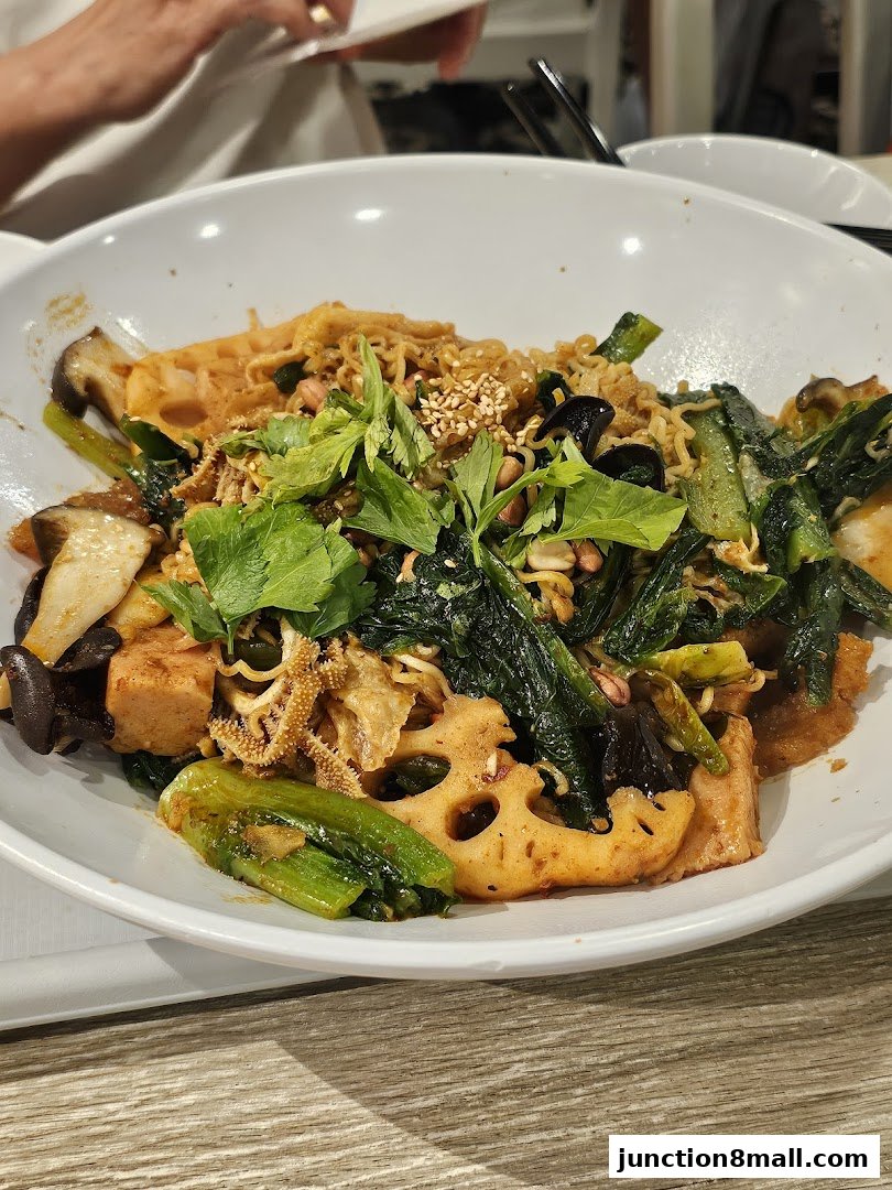 A close-up of a flavorful mala hot pot dish with noodles, vegetables, and tripe.