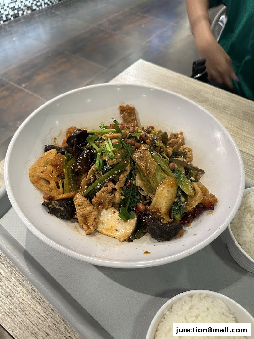 A close-up of a flavorful mala hot pot dish with various ingredients and a side of rice.