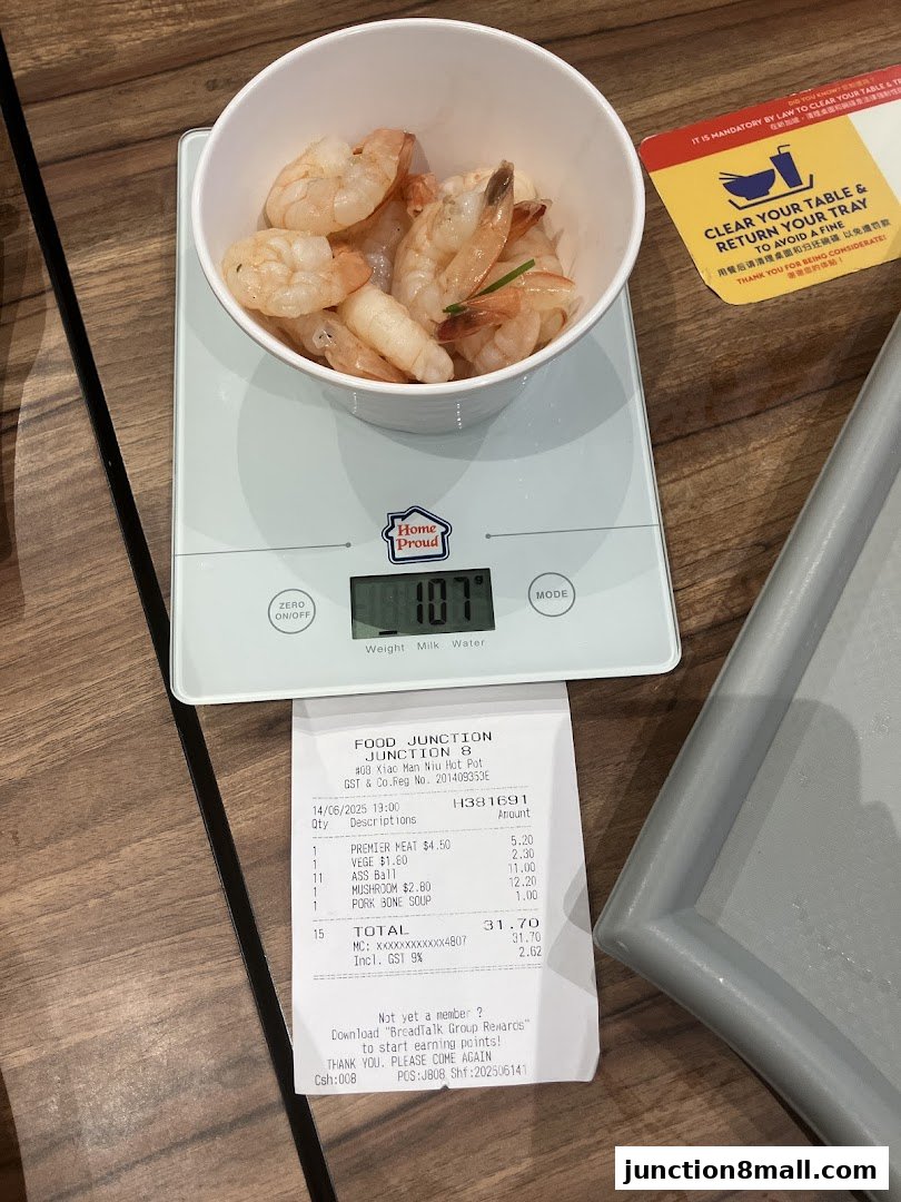A bowl of cooked shrimp is weighed on a digital scale next to a receipt.