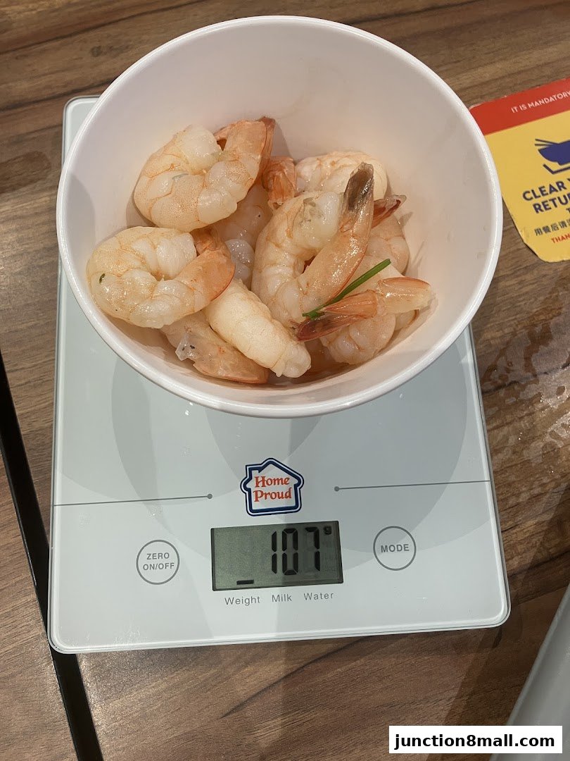 A bowl of cooked shrimp is weighed on a digital scale.