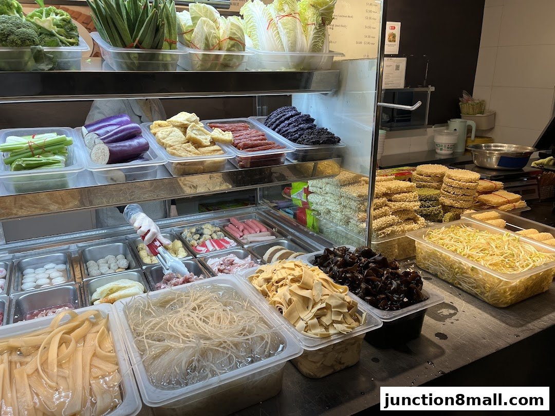 A display of fresh ingredients for Mala Hot Pot, including vegetables, meats, and noodles.