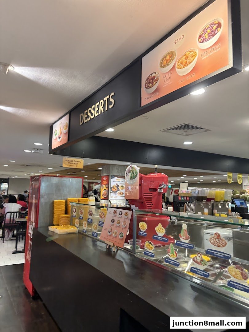 A dessert counter with various colorful bowls of desserts and a sign that says 'DESSERTS'.