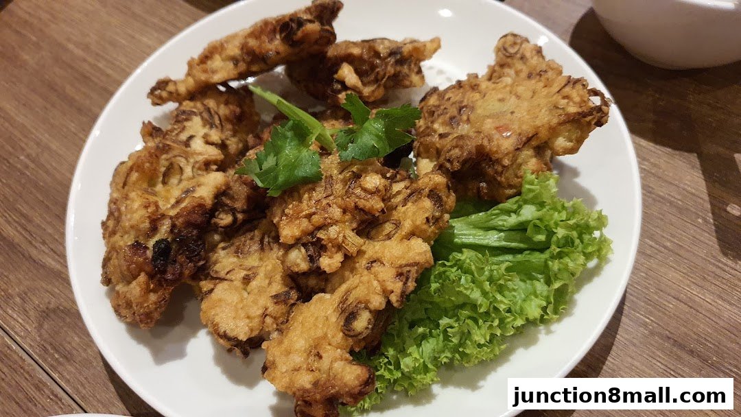 A plate of crispy fried fritters garnished with lettuce and cilantro on a wooden table.