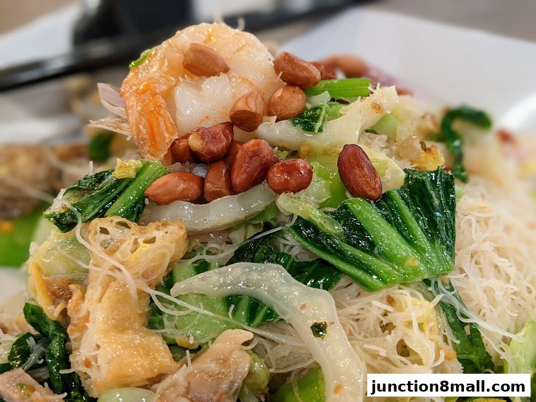 A close-up of a delicious noodle dish with shrimp, vegetables, and peanuts.