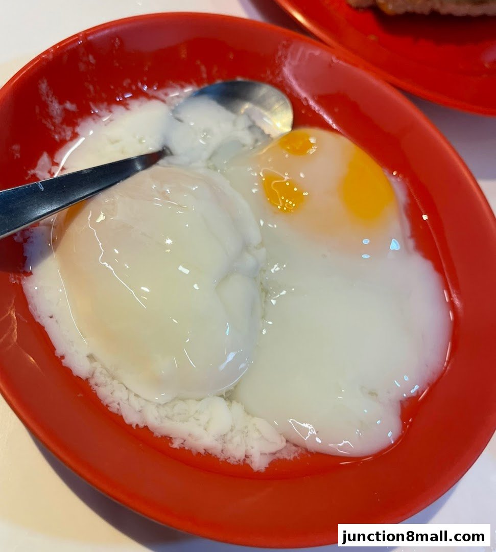 A close-up shot of two soft-boiled eggs served in a red bowl with a spoon.