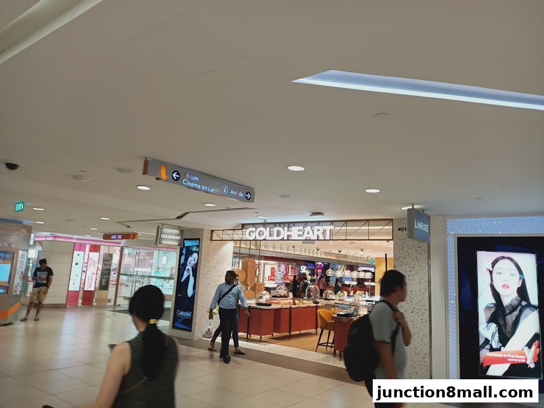 A shopping mall interior with various shops and people walking.