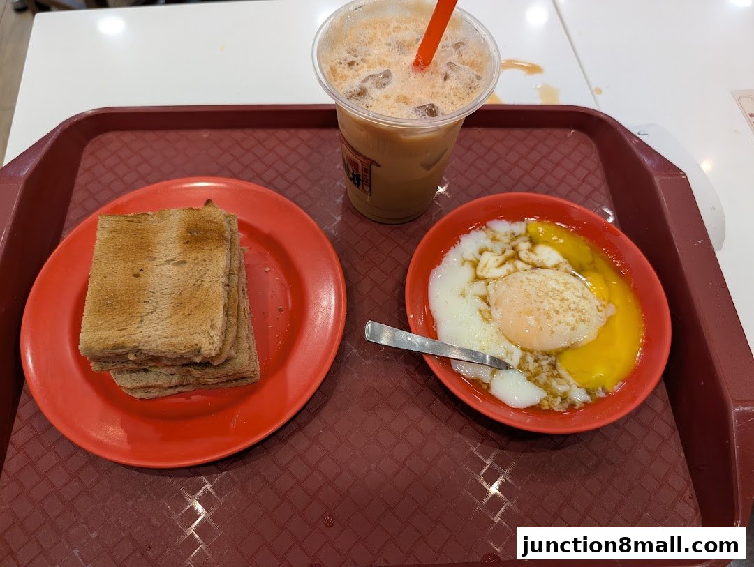A tray with Ya Kun Kaya Toast's signature kaya toast, soft-boiled eggs, and a milk tea.