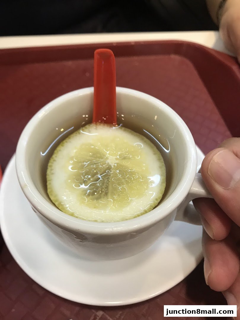 A close-up shot of a cup of tea with a lemon slice and a red spoon.