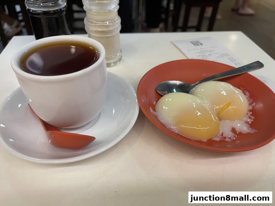 A cup of coffee and two soft-boiled eggs on a table at Ya Kun Kaya Toast.