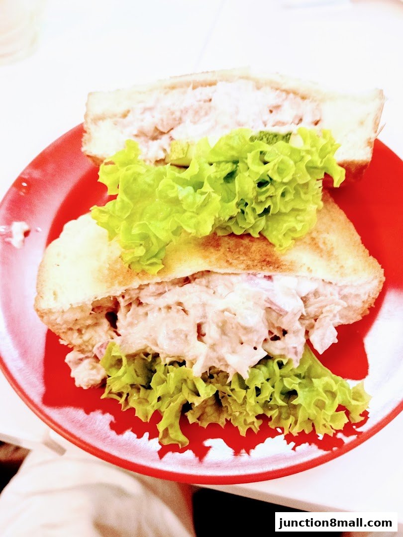 A close-up shot of a tuna sandwich with lettuce on a red plate.