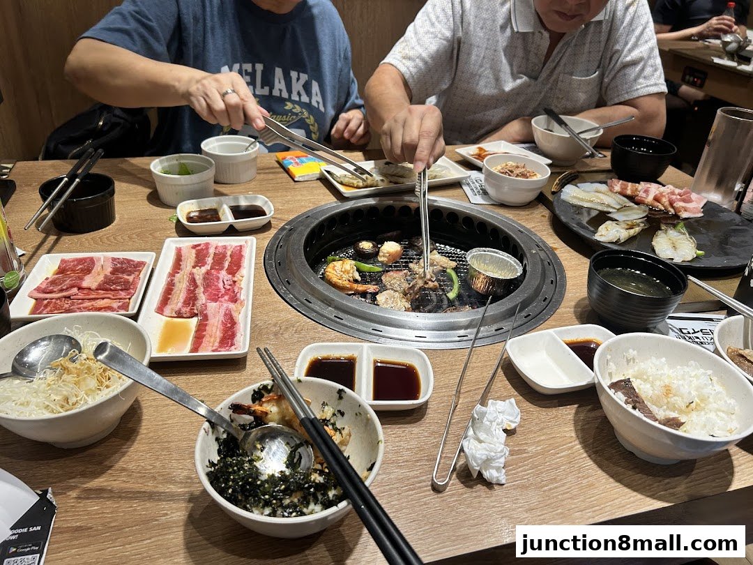 People enjoying a Yakiniku meal with grilled meats, rice, and dipping sauces at a table.