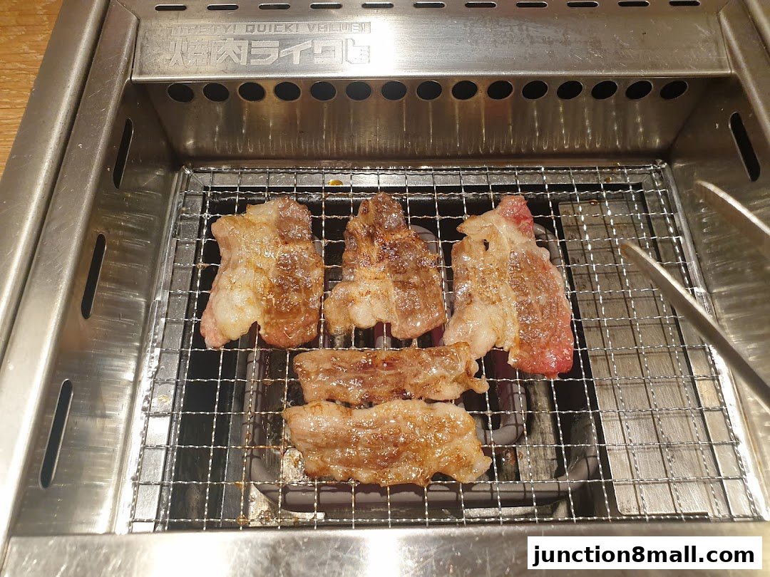 Sizzling slices of beef are grilled on a metal grate over a heat source.
