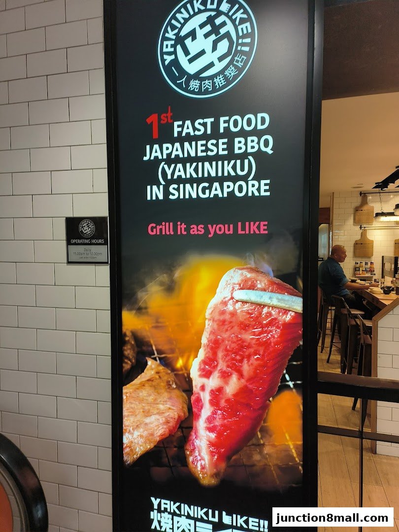 A vertical sign for Yakiniku Like featuring a close-up of grilling meat and operating hours.