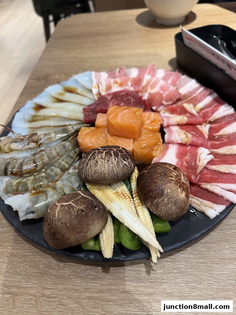 A platter of assorted raw meats, seafood, and vegetables for grilling.