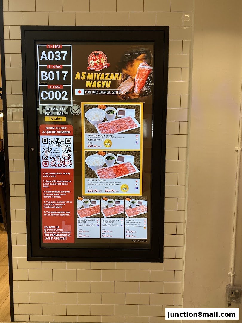 A digital menu board displaying queue numbers and various wagyu beef sets with prices.