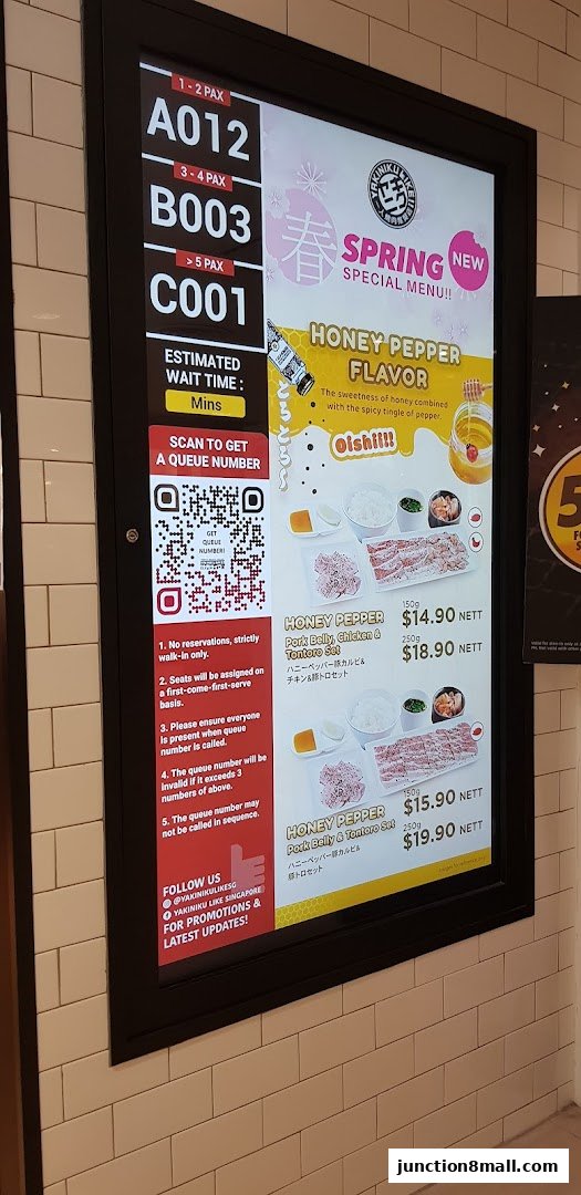 A digital menu board displaying queue numbers and Yakiniku Like's Spring Special Menu.