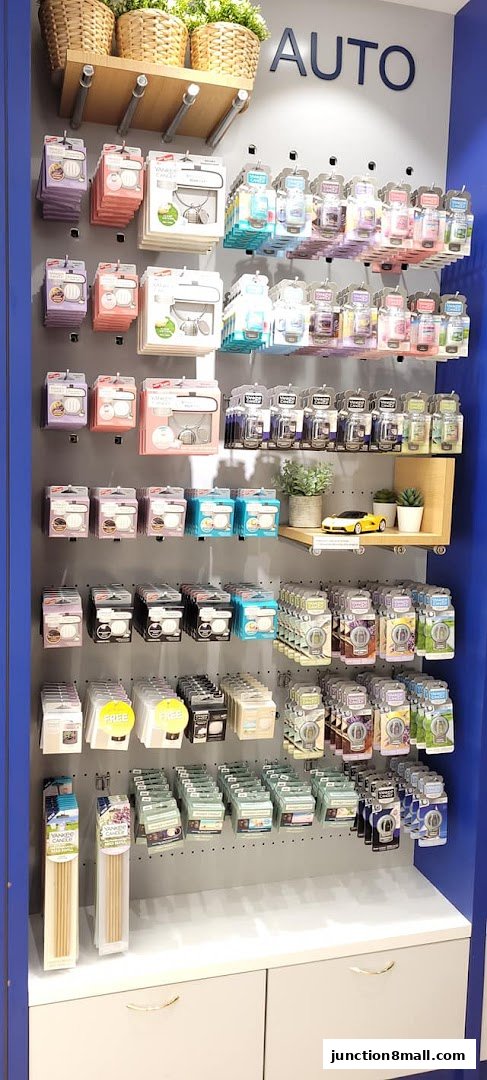 A wall display featuring various Yankee Candle car air fresheners and other car accessories.