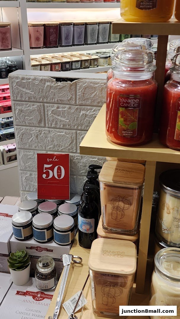 A display of Yankee Candle products, including large jars and smaller candles, with a sale sign.
