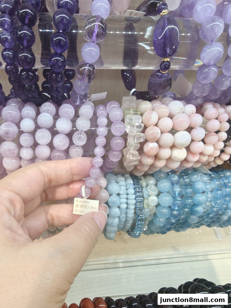A hand holds a bracelet with a price tag, surrounded by colorful gemstone bracelets.