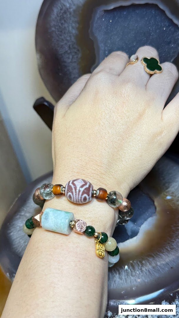 Close-up of hands wearing bracelets and a ring, showcasing unique gemstone designs.