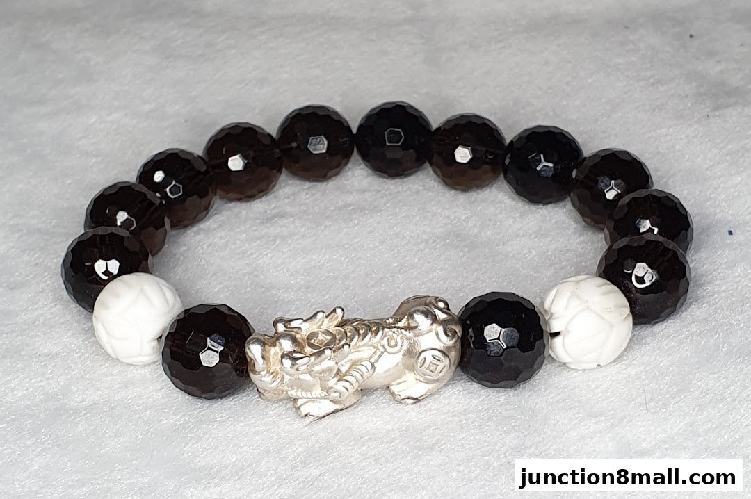 A bracelet with faceted dark beads, white carved beads, and a silver mythical creature charm.