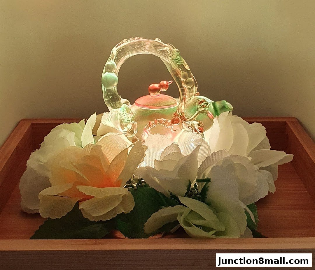 A decorative glass teapot with floral accents on a wooden tray.