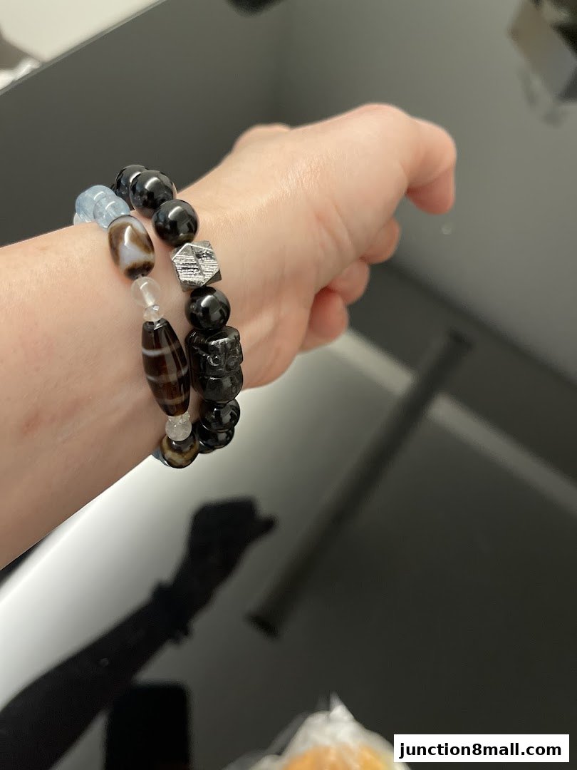 A person's wrist adorned with two stylish beaded bracelets featuring unique charms.