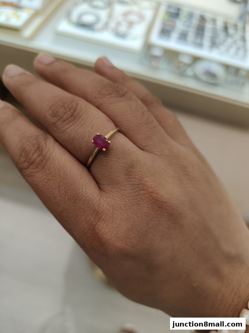 A hand wearing a gold ring with a ruby gemstone, showcasing elegant jewelry.